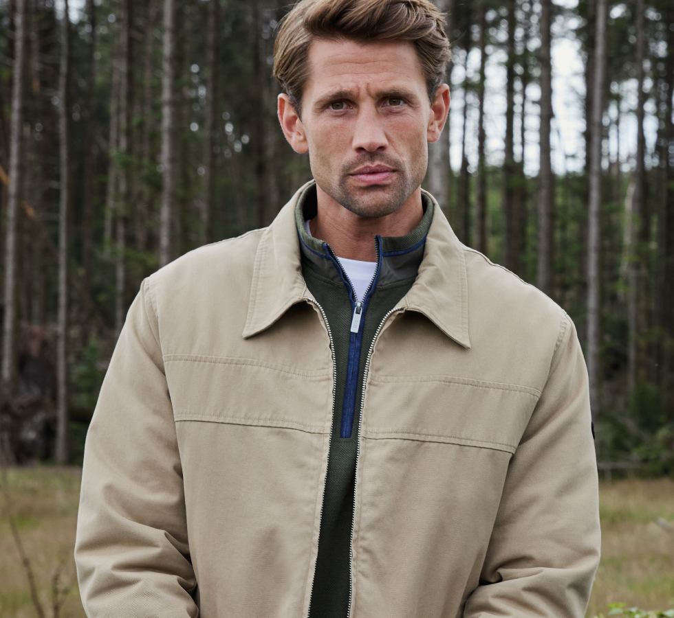 Man wearing suede, casual jacket and green quarter zip