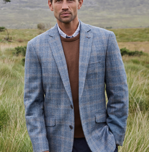 Man wearing grey, checkered blazer and brown crewneck sweater